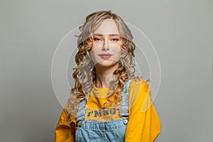 Cute blonde woman smiling on gray background