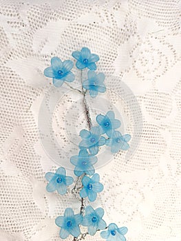 cute blue artificial flowers on the white lace background photo