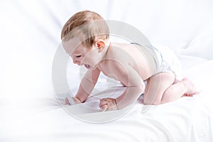 Cute blue-eyed baby 6-9 months playing on white background. Children`s emotions. Cleanliness and care for babies