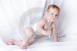 Cute blue-eyed baby 6-9 months playing on white background. Children`s emotions. Cleanliness and care for babies