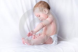 Cute blue-eyed baby 6-9 months smiling and playing on white background. Cleanliness and care for babies