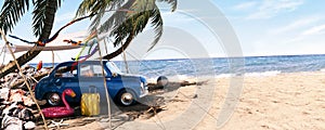 Cute blue retro car with summer accessories and palm tree on beautiful tropical sand beach. Summer vacation concept.