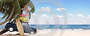 Cute blue retro car with summer accessories and palm tree on beautiful tropical sand beach. Summer vacation concept