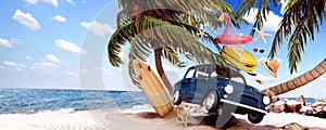 Cute blue retro car with summer accessories and palm tree on beautiful tropical sand beach. Summer vacation concept.