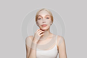 Cute bonde woman touching her face isolated on grey background., cosmetics, skincare, glamour photo