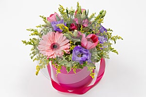 Cute bouquet pink, yellow, green, purple of roses, eustoma, gerberas and greenery in a round pink cardboard box
