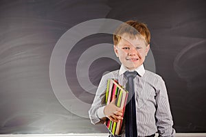 Cute boy against blackboard