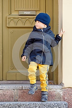 Cute boy on an autumn day at the door of the old post office