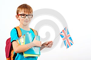 Cute boy with backpack and books holds British flag. Student learning english. English language school