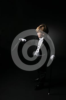 Cute boy in black tuxedo and white gloves