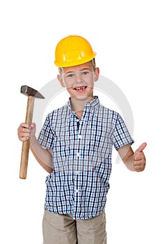 Cute boy in blue checkered shirt and yellow building helmet, holding a hammer in one hand and showing thumbs up