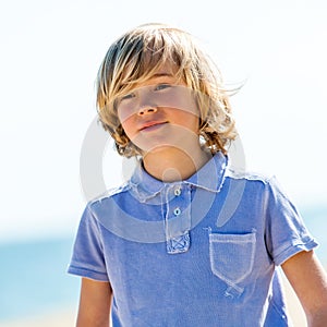 Cute boy with blue polo shirt outdoors.