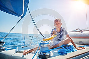 Little boy on board of sailing yacht on summer cruise. Travel adventure, yachting with child on family vacation. photo