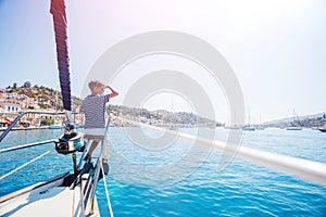 Little boy on board of sailing yacht on summer cruise. Travel adventure, yachting with child on family vacation. photo