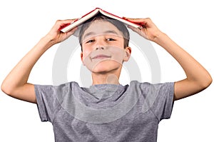 Cute boy with a book on his head smiling on white background