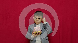 Cute boy in business suit holding piggy bank and getting frustrated as it is empty. Savings investment and recession