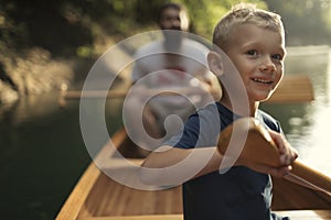 Cute boy canoeing on the lake with his dad