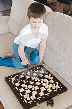 A cute boy of Caucasian appearance plays chess. Games for the development of logic and strategy. Chess tournaments photo