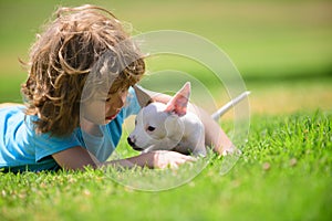 Cute boy child with her doggy lying on lawn. Kids with her pet friend.