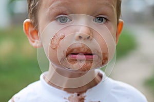 Cute boy with chocolate ice cream on face. Kid with a dirty face after he ate icecream