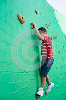 Cute boy climbing wall at playground