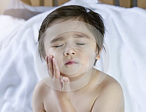 Cute boy closing eyes while applying body lotion cream on his cheek after shower,Kid using cream for skincare protection,Child moi