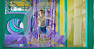 Cute boy crawling and playing on colorful playground at indoor amusement park