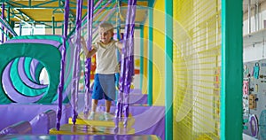 Cute boy crawling and playing on colorful playground at indoor amusement park