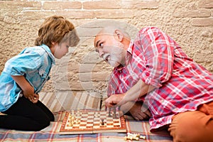 Cute boy developing chess strategy. Cute little boy playing chess. Chess competition. Grandfather and grandson playing