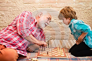 Cute boy developing chess strategy. Cute little boy playing chess. Chess competition. Grandfather and grandson playing