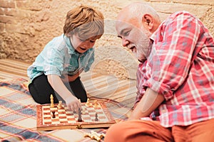 Cute boy developing chess strategy. Mature man with little boy playing chess. Little boy playing chess with his