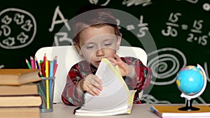 Cute boy doing homework, coloring pages, writing and painting. Children paint. Kids draw. Preschooler with books at home