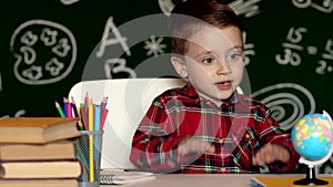 Cute boy doing homework, coloring pages, writing and painting. Children paint. Kids draw. Preschooler with books at home