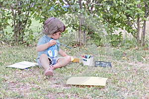 Cute boy doing homework laying on grass. Child reading a book in the summer park. Concept of kids learning, study