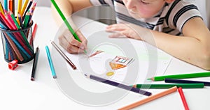 Cute boy drawing on a piece of paper with color pencils at home or classroom