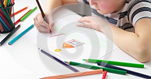 Cute boy drawing on a piece of paper with color pencils at home or classroom