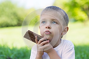 Cute boy is eating a chocolate bar