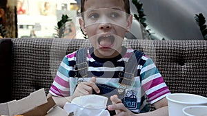 Cute boy eating pizza at cafe frome the box