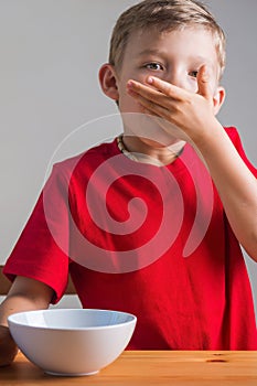 Cute boy eats granola for breakfast. Lifestyle portrait.