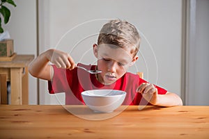 Cute boy eats granola for breakfast. Lifestyle portrait.