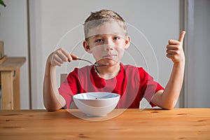 Cute boy eats granola for breakfast. Lifestyle portrait.