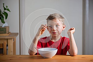 Cute boy eats granola for breakfast. Lifestyle portrait.