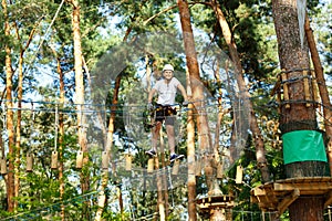 Cute boy enjoying activity in climbing adventure park at sunny summer day. Kid climbing in rope playground structure.