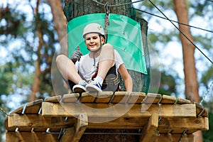 Cute boy enjoying activity in climbing adventure park at sunny summer day. Kid climbing in rope playground structure.