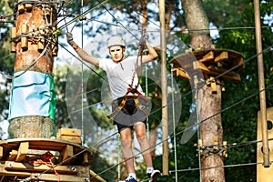 Cute boy enjoying activity in climbing adventure park at sunny summer day. Kid climbing in rope playground structure