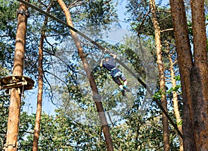 Cute boy enjoying activity in climbing adventure park at sunny summer day. Kid climbing in rope playground structure.