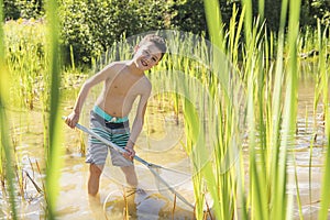 Cute Boy fishing with a net on a lake