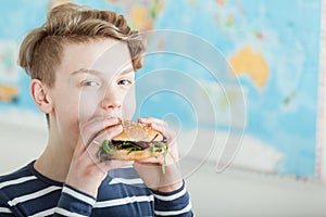 Cute boy in front of map while eating a burger