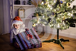 A cute boy with a gift box near Christmas tree