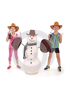 Cute boy and girl holding a cola bottle near a snowman with scarf and hat